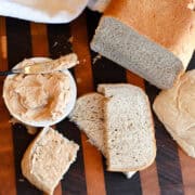 Overhead view of sliced cinnamon bread with cinnamon honey butter on a wooden cutting board in a cozy kitchen setting
