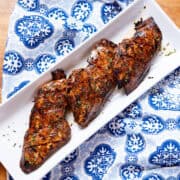 Grilled chicken breasts with char marks, garnished with herbs ready to serve on white platter