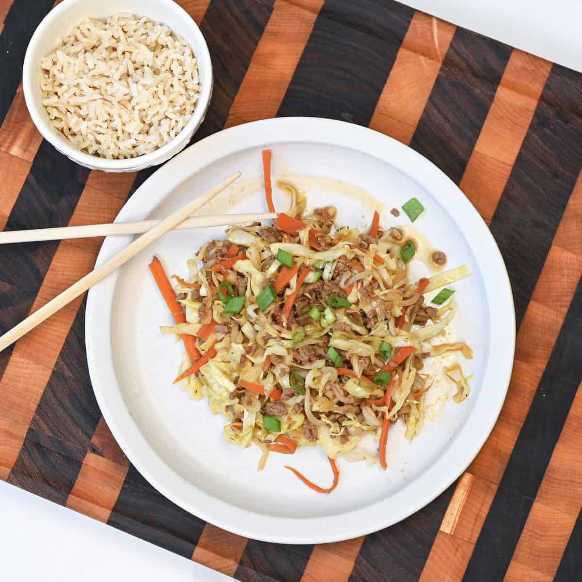 Egg Roll in a Bowl served on a white plate with fluffy white rice, featuring seasoned ground turkey, shredded cabbage, and carrots cooked until tender.