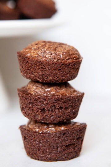 Stack of mini brownie bites on a white plate with a rustic background