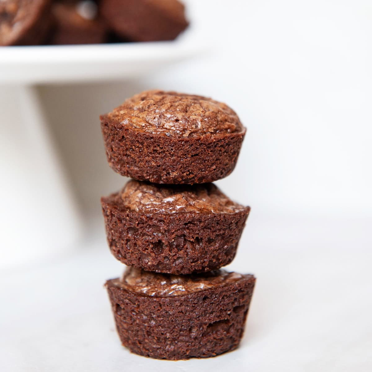 Stack of mini brownie bites on a white plate with a rustic background