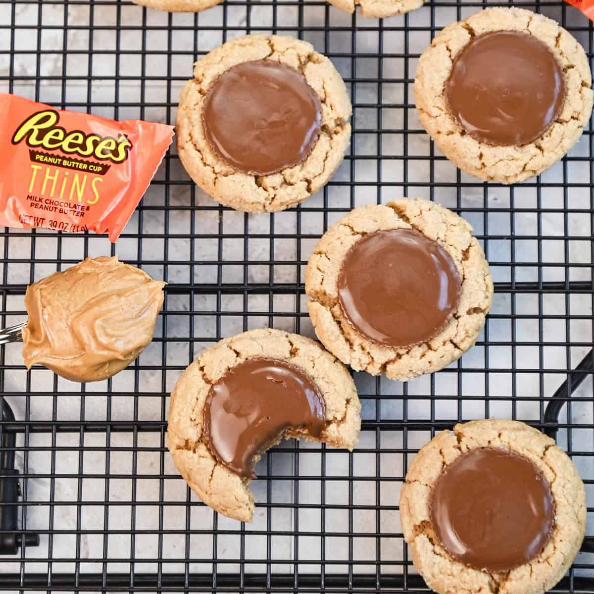 Close-up of a peanut butter cookie with a perfectly melted Reese’s Thins candy in the center.