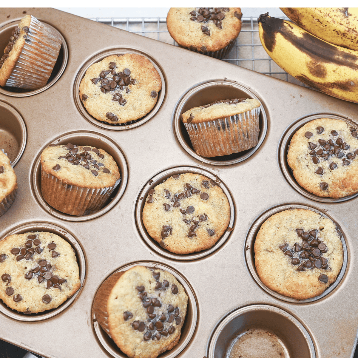 Muffins scattered across a muffin pan, highlighting their rustic homemade look.