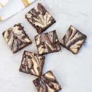 Flat lay of marbled brownies cut into squares on a kitchen counter.