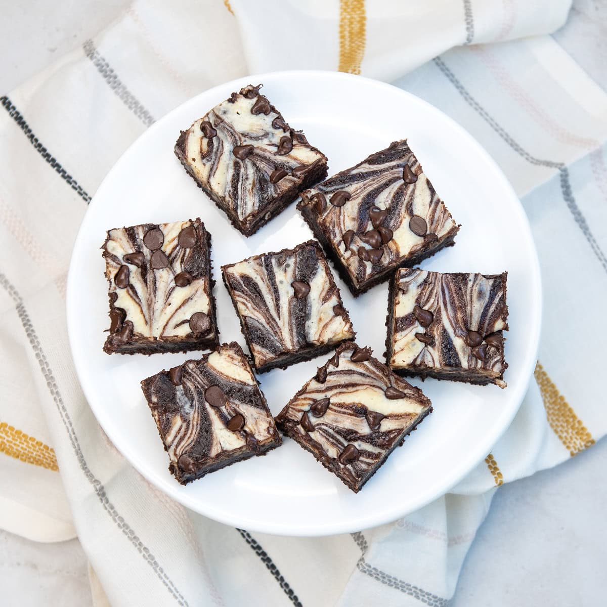 Squares of marbled brownies arranged neatly on a white platter