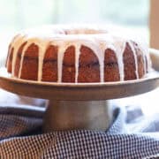 Glazed Sock It to Me cake on a cake stand, close-up angle showing the bundt shape and glossy topping.