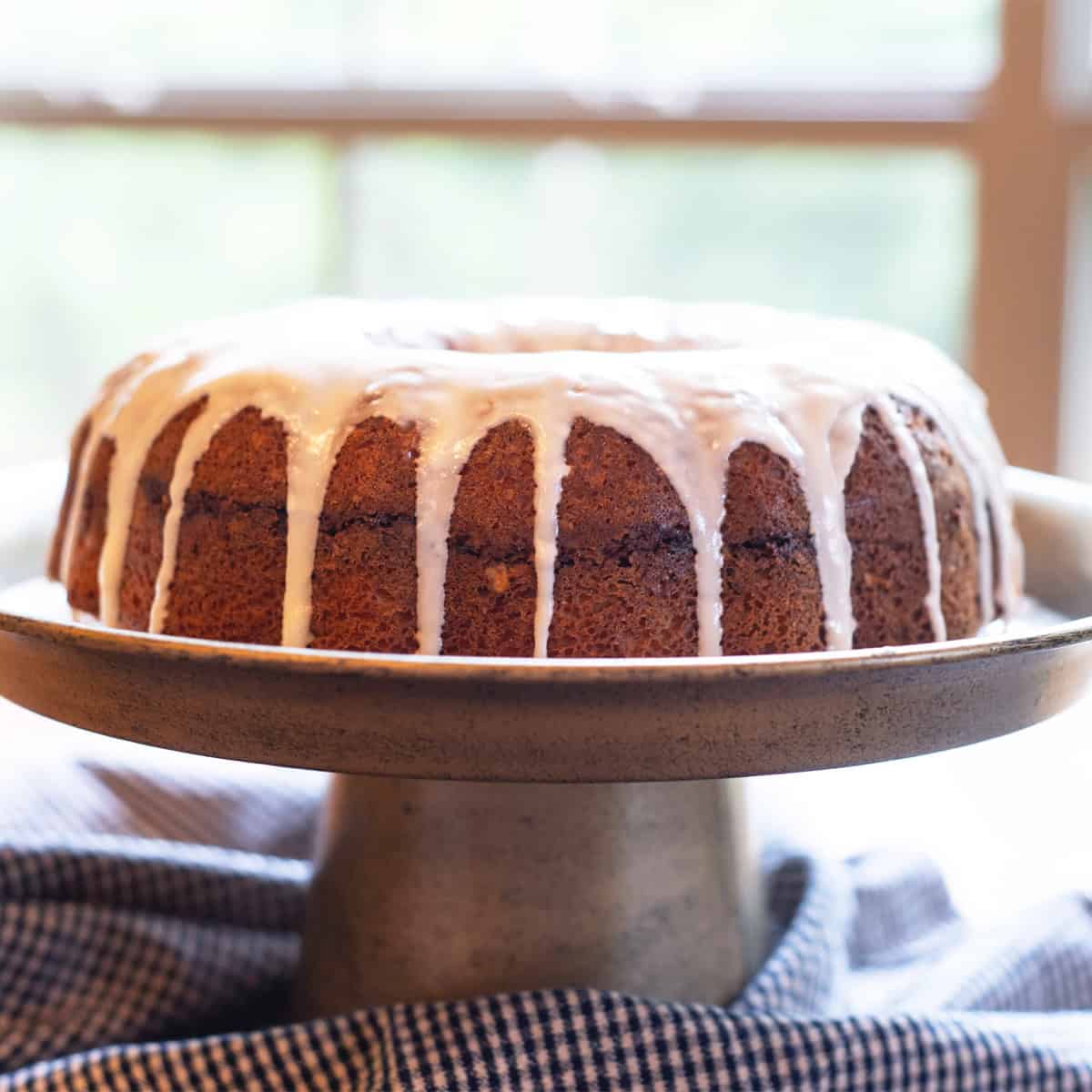 Whole Sock It to Me bundt cake on a stand topped with thick glaze, photographed from the front angle