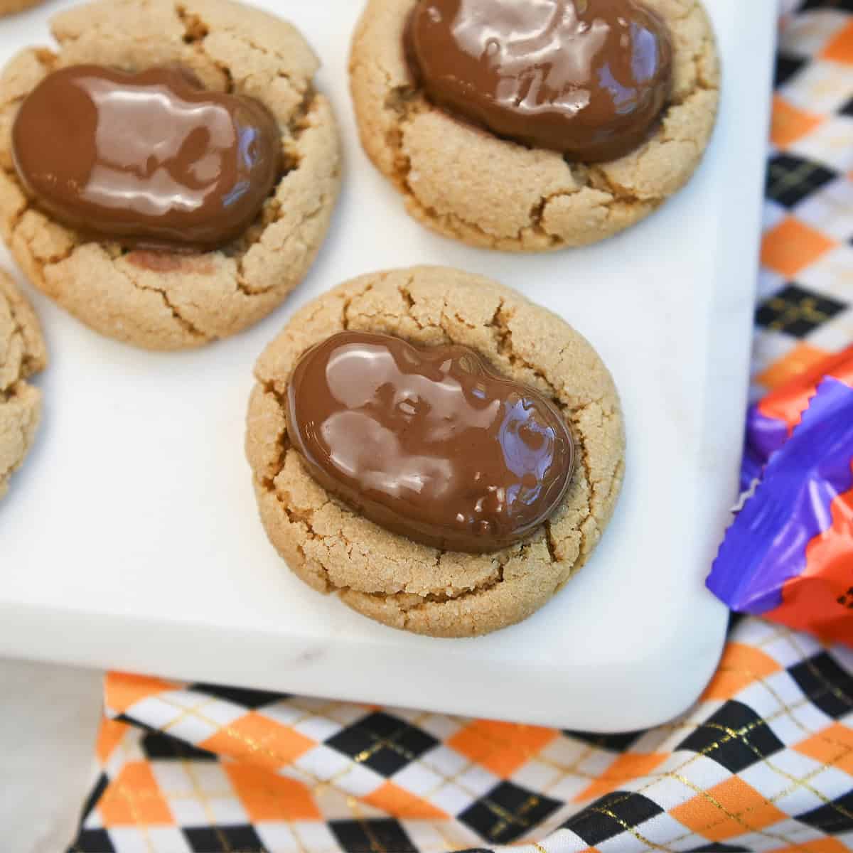 Macro view of a single Halloween Reeses cookie showing creamy peanut butter texture and chocolate pumpkin candy on top.