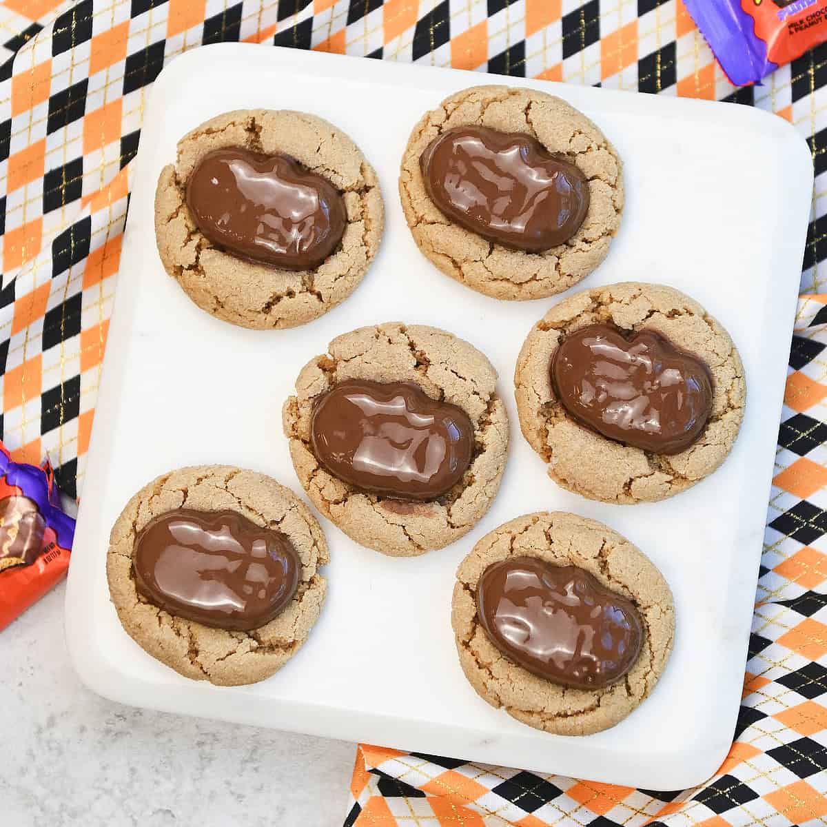 Close-up of Halloween Reeses peanut butter cookies with Reese’s pumpkins on top, showing soft texture and chocolate detail.