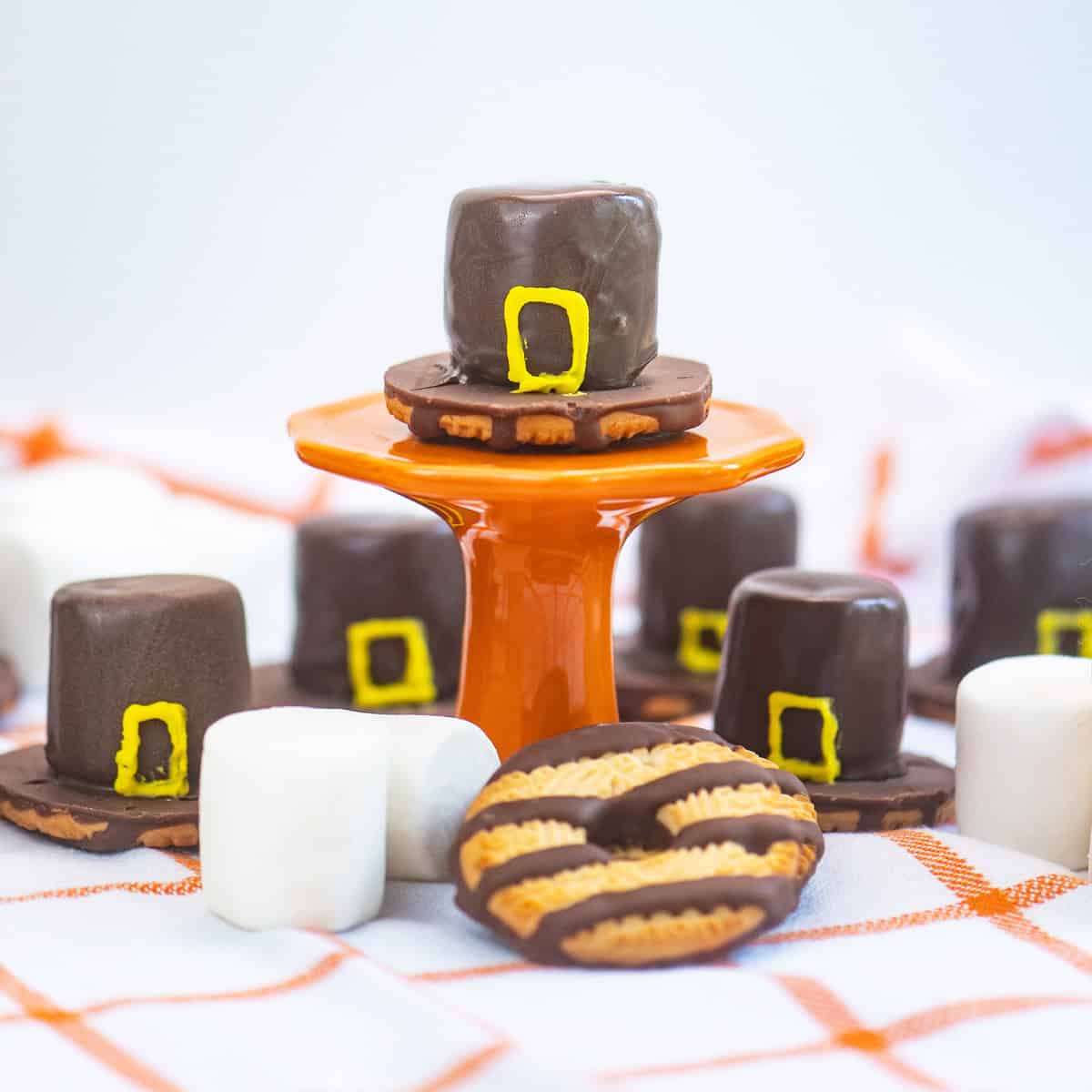 Close-up of a chocolate-covered marshmallow Pilgrim hat on a bright orange pedestal.