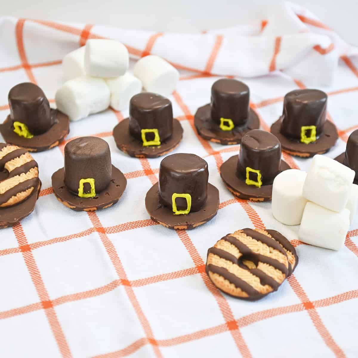 Overhead view of chocolate-dipped marshmallow Pilgrim hats arranged neatly on a flat surface.