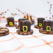 Chocolate marshmallow Pilgrim hats in front of a colorful and festive Thanksgiving backdrop.