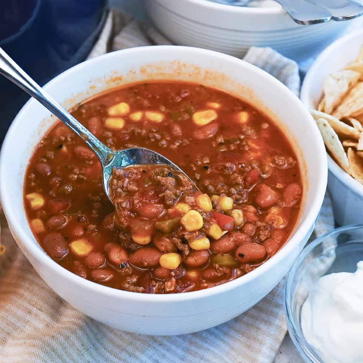 Close-up of a spoonful of taco soup showing beef, beans, corn, and melted cheese.