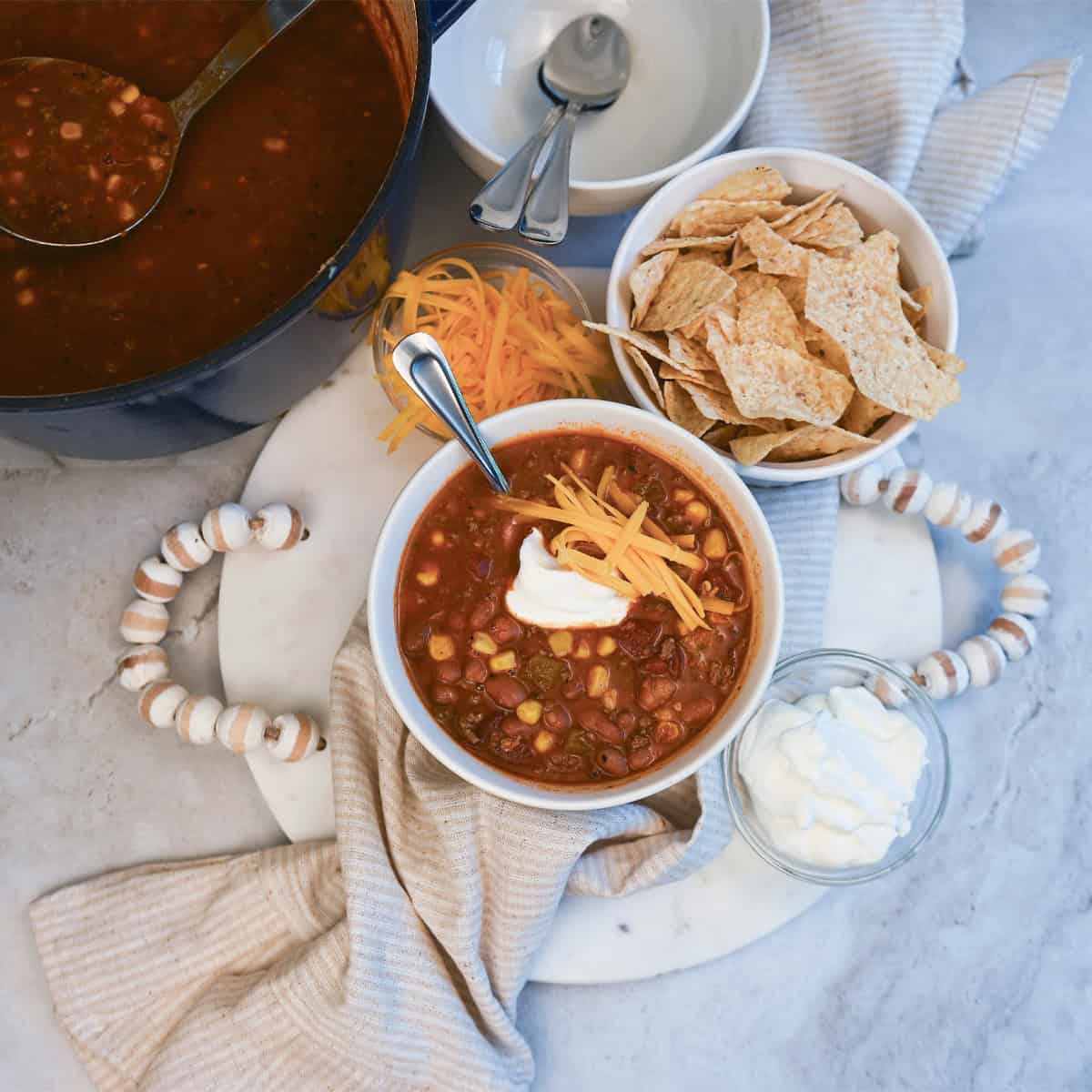 Bowls of taco soup topped with shredded cheese, sour cream, and tortilla chips for a hearty and flavorful meal.
