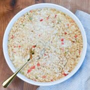 White Corn Casserole in a white dish with a tan tea towel, ready to serve.