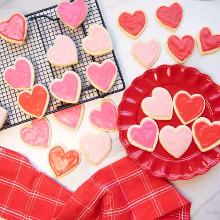 Iced Valentine sugar cookies displayed on a festive Valentineโs Day tablescape with pink and red accents.