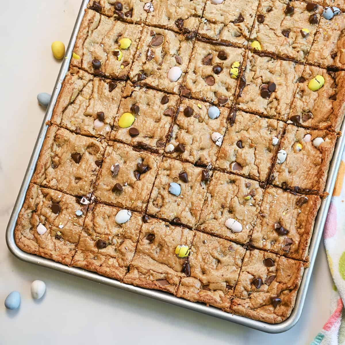 Cadbury Egg cookie bars cut into squares in a baking pan showing soft centers and chocolate chips.