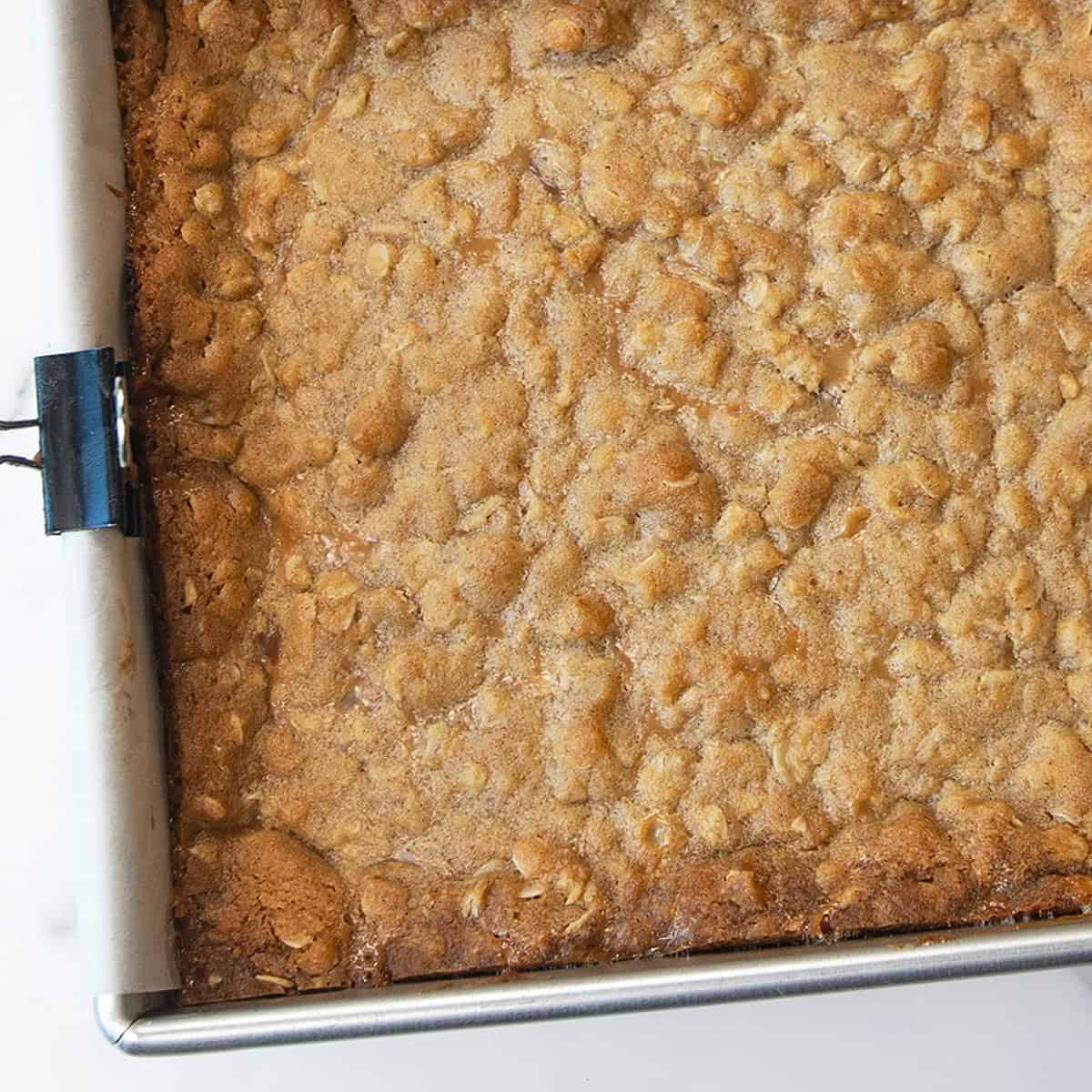 Baked pan of Carmelitas with golden oatmeal crust and gooey caramel chocolate layers.