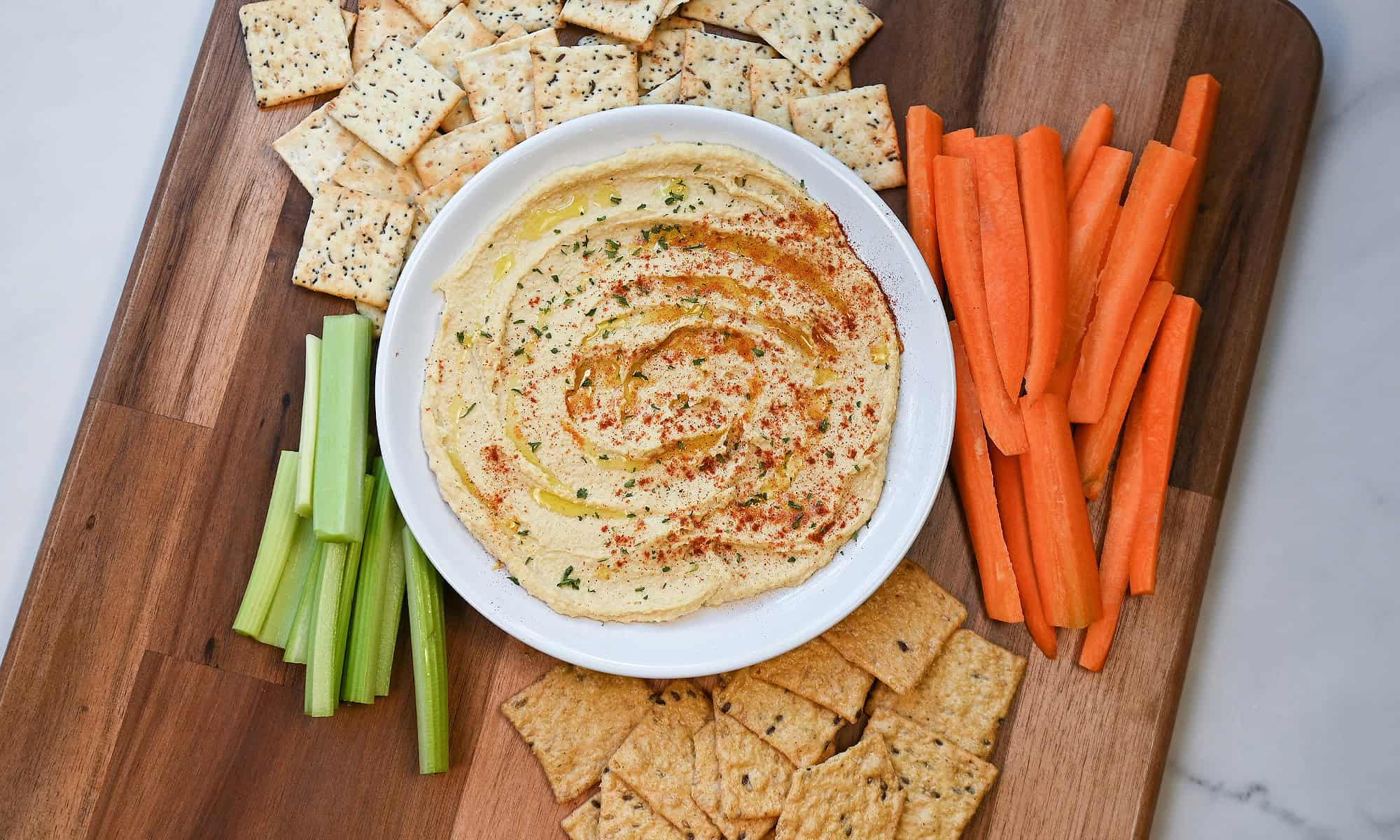 Overhead view of a bowl of smooth hummus drizzled with olive oil and sprinkled with seasoning.