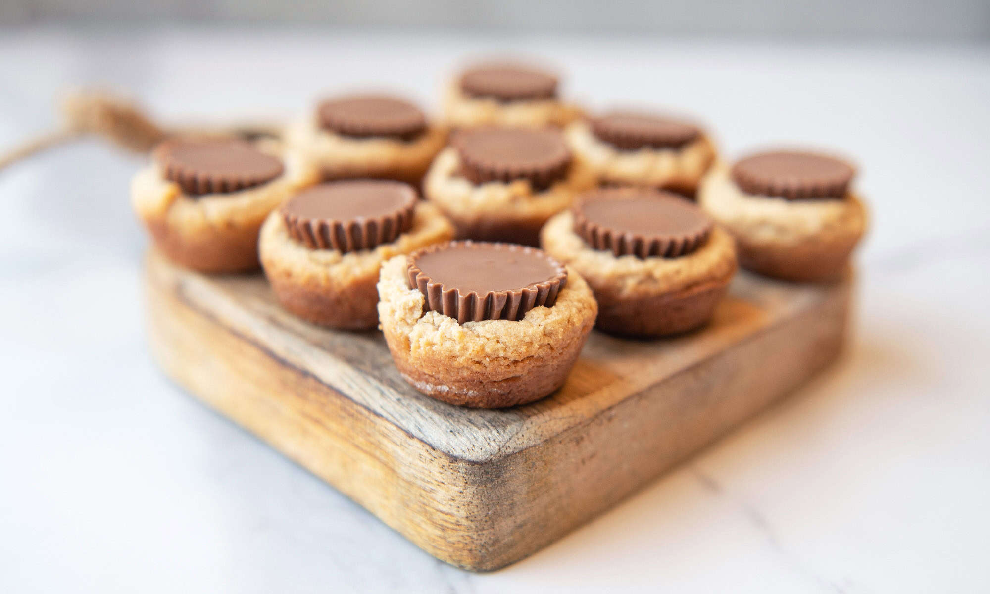 Side angle view of peanut butter cup cookies displayed on a wooden board.