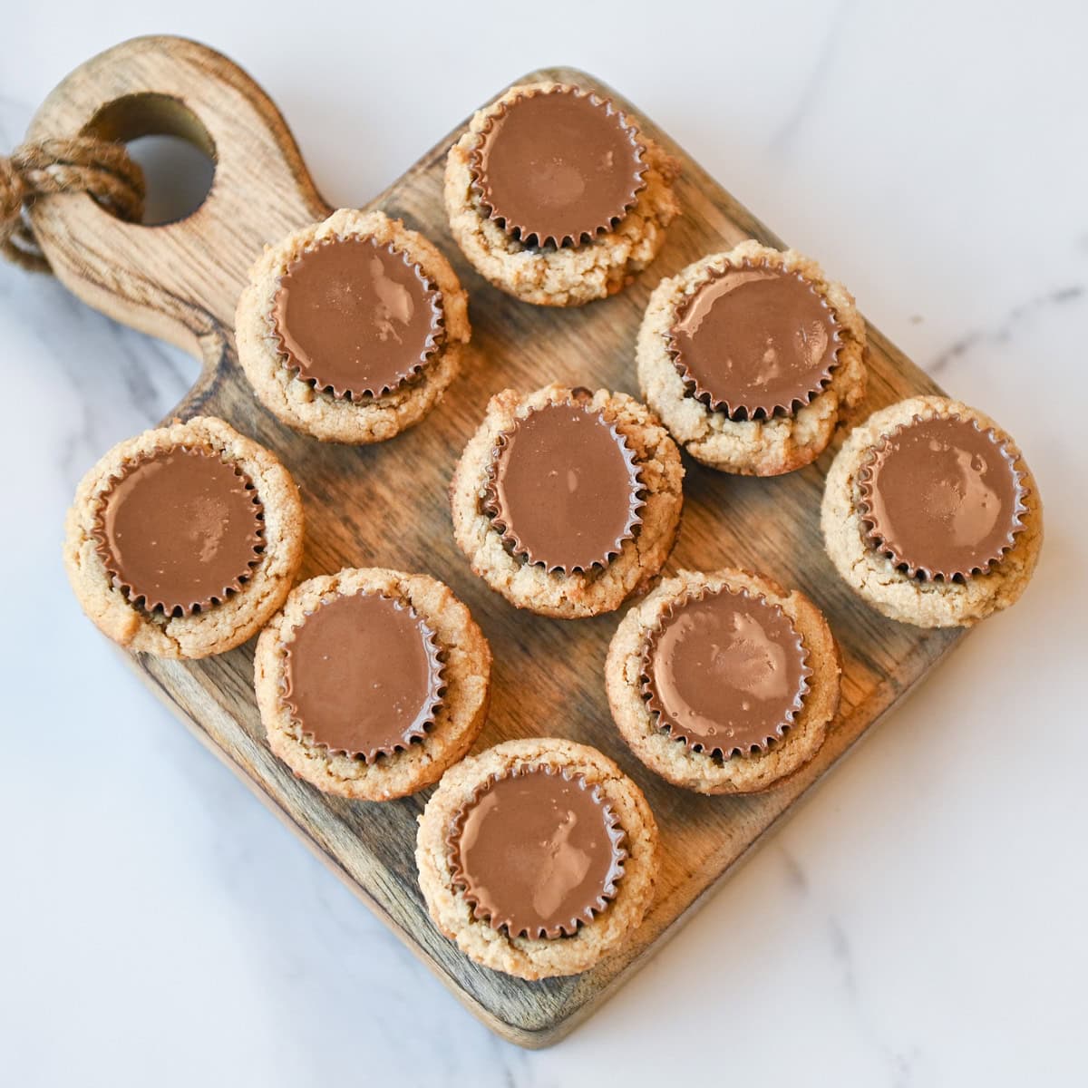 Overhead view of peanut butter cup cookies arranged on a wooden serving board.