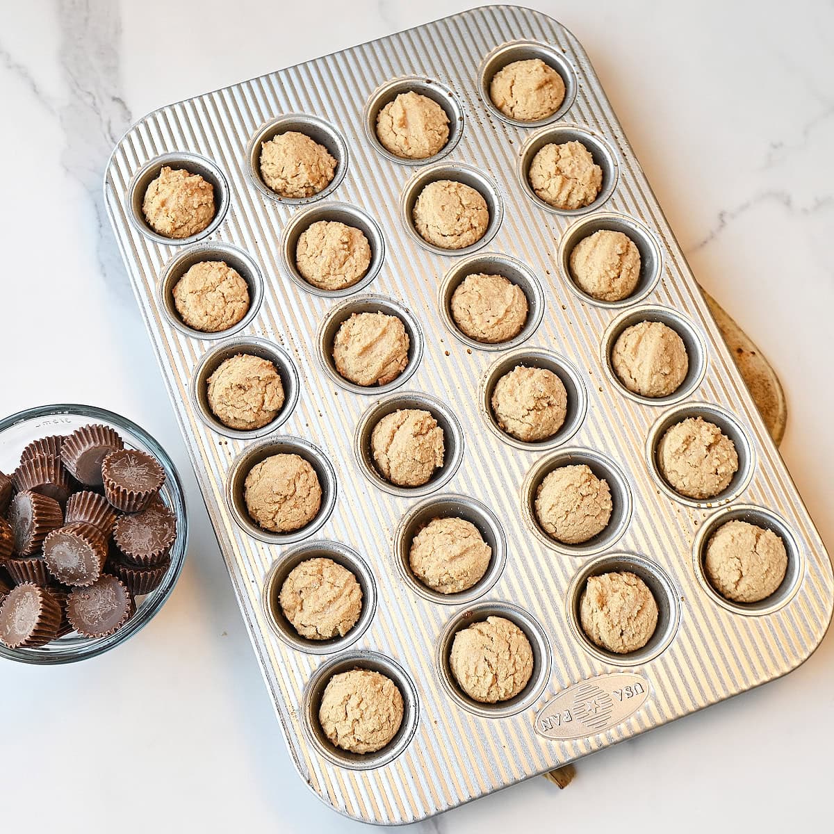 mini muffin pan showing baked peanut butter cup cookies ready to have candy