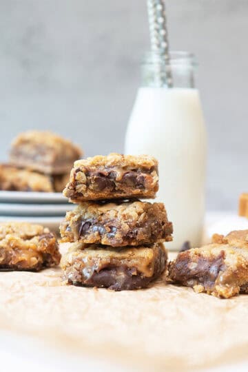 Stack of Carmelitas bars served with a glass of milk showing gooey caramel and chocolate layers.