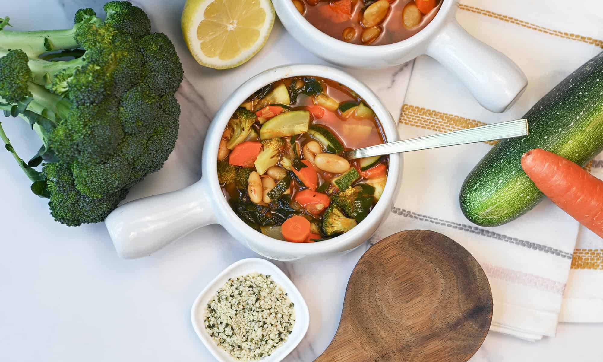 Two white bowls filled with healthy white bean vegetable soup.