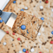 Close-up of a soft and chewy patriotic M&M cookie bar with melted chocolate chips and colorful M&Ms.