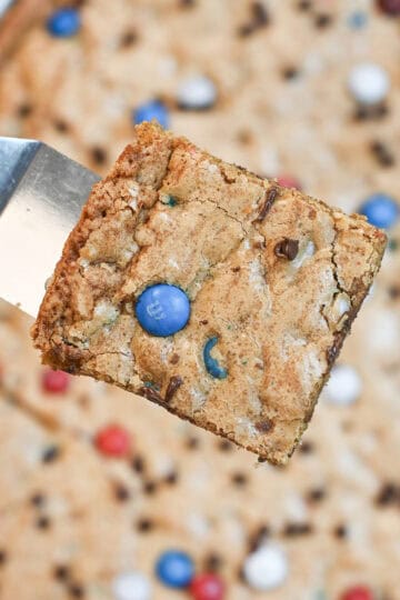 Close-up of a soft and chewy patriotic M&M cookie bar with melted chocolate chips and colorful M&Ms.