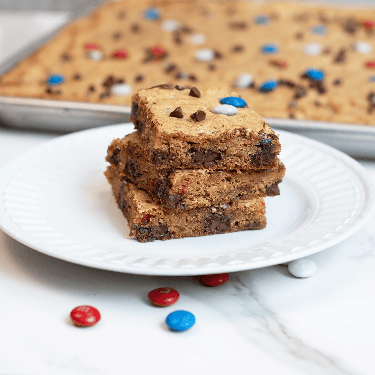 Angled side view of three stacked patriotic M&M cookie bars showing soft centers and chocolate chips.