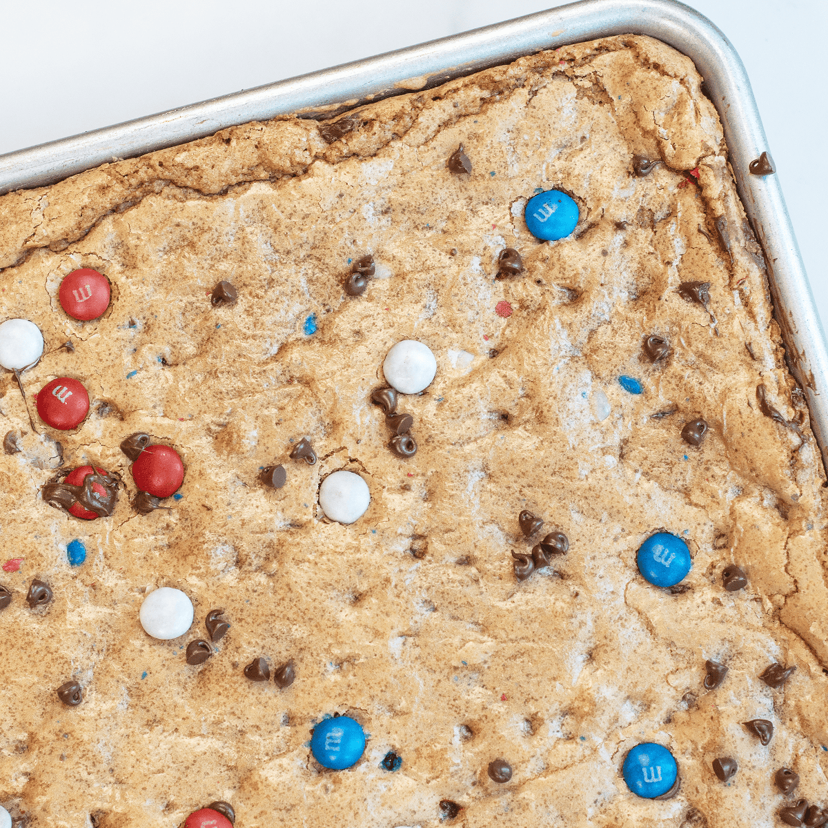 Close-up of the corner of patriotic M&M cookie bars showing golden edges and soft crackly tops.
