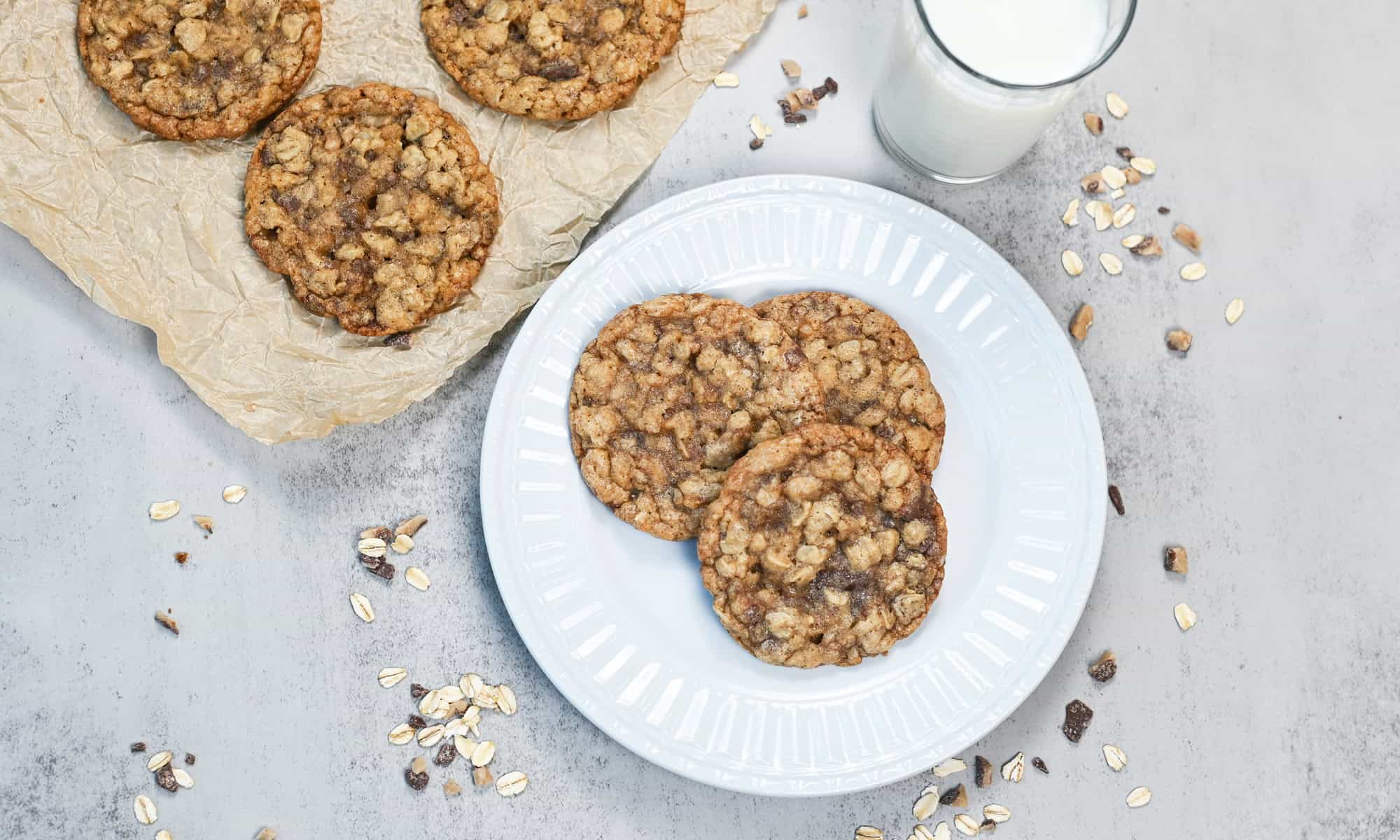 Plate of chewy oatmeal toffee cookies served with a glass of milk for a classic homemade dessert.