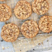 Overhead view of chewy oatmeal toffee cookies cooling on a wire rack with melted toffee pieces and golden brown edges.
