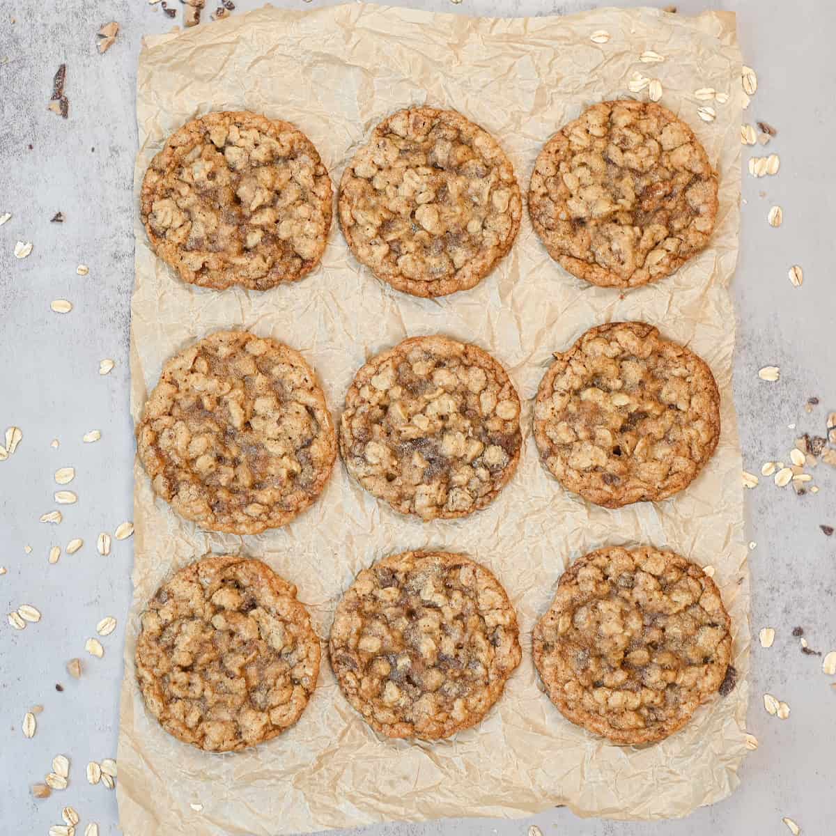 Nine oatmeal toffee cookies arranged on parchment paper showing their golden brown color and chewy texture.
