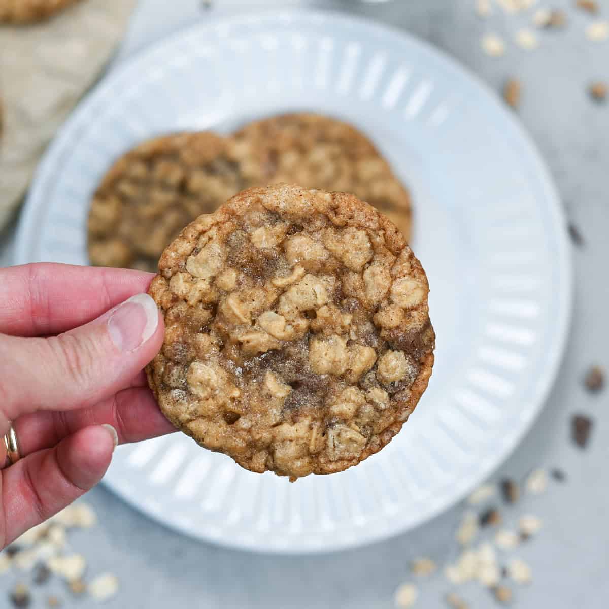 Close-up of a chewy oatmeal toffee cookie showing its soft center, old-fashioned oats, and melted toffee pieces.